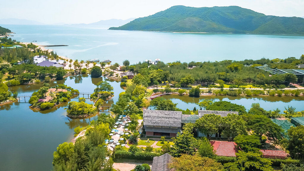 Nghinh Xuan Lake with poetic monkey bridges crossing, the lake surface silhouetted by rows of graceful trees against the blue sky